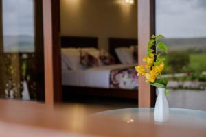 a vase with yellow flowers on a table in a bedroom at Summer Vines - Nashik in Pandhurli +13 photos