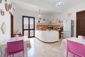 a kitchen with two tables and a white refrigerator at Demetra Malophoros in Marinella di Selinunte