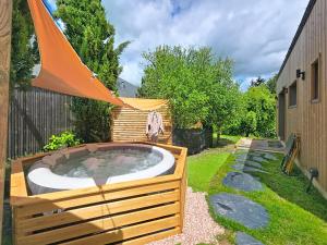 a hot tub in a garden with an umbrella at Maisonnette d'architecte face nature, 15min de Tours in Charentilly