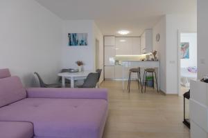 a living room with a purple couch and a kitchen at Enamare mit Terrasse in Šimuni