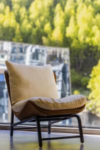 a chair with a pillow sitting in front of a window at Jianshanxi Designer Hotel in Mount Siguniang