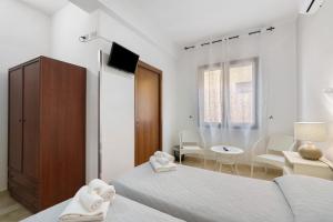 a white room with two beds and a table at Demetra Malophoros in Marinella di Selinunte