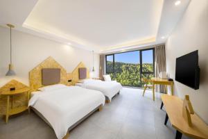 two beds in a hotel room with a view at Jianshanxi Designer Hotel in Mount Siguniang