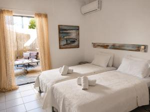 two beds in a white room with a window at Votsalon Beach House - 30 meters from Alykes Beach in Katastárion