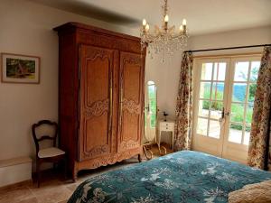 a bedroom with a large wooden cabinet and a chandelier at Les Volets Verts-Dordogne in Plazac