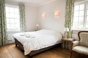 a bedroom with a bed and a chair and windows at The Old Rectory in Campsey Ash
