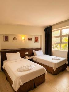 a hotel room with two beds with white sheets at New century inn in Bintulu