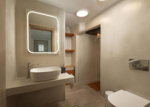 a bathroom with a sink and a mirror and a toilet at Falcon Eyes- Panoramic stone house in Andros +11 photos