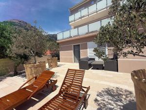 two wooden benches sitting in front of a building at Villa Nikola - pool side apartments in Bol
