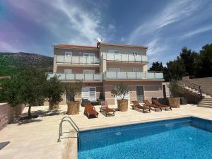 a building with a swimming pool in front of a house at Villa Nikola - pool side apartments in Bol