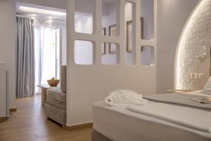 a white bedroom with a bed and a chair at Valetta Inn in Naxos Chora +95 photos