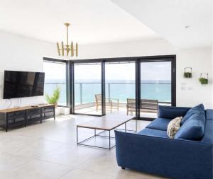 a living room with a blue couch and a table at Magical 4BR APT With Panoramic Sea View l Mamad in Bat Yam