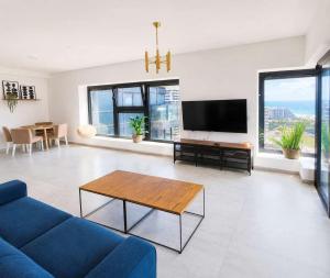 a living room with a blue couch and a tv at Magical 4BR APT With Panoramic Sea View l Mamad in Bat Yam +35 photos