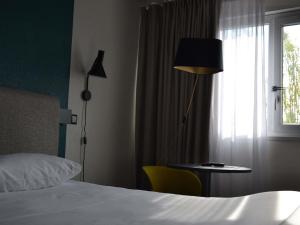 a bedroom with a bed and a table and a window at ibis Chambery in Chambéry