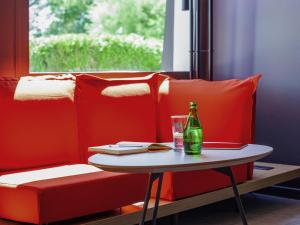 a bottle of beer on a table next to a couch at ibis Mulhouse Ile Napoleon in Sausheim