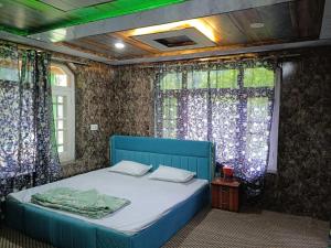 a blue bed in a room with curtains at Paris Home Stay in Keran
