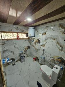 a bathroom with a marble wall with a toilet at Paris Home Stay in Keran