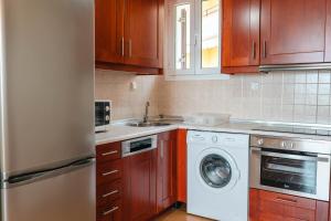 a kitchen with wooden cabinets and a washer and dryer at Corfu Glyfada Beach Apartment 58a in Corfu