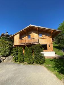 a large wooden house with a balcony and a driveway at Chalet Charline in Combloux