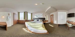 a large bedroom with a bed and a desk at JOESEPP´S HOTEL am Schweizerberg in Memmingen