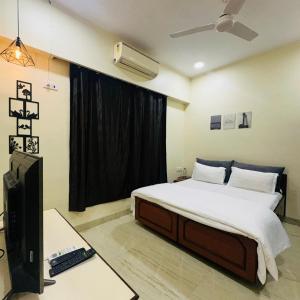 a bedroom with a bed and a desk and a television at StayLuxe Rooms & Apartments Near BKC, Chembur in Mumbai