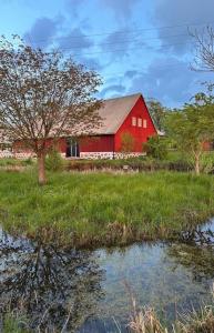a red barn sitting in a field next to a pond at Gunnegårds gästhus in Fleninge
