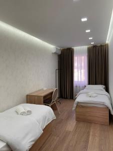 a hotel room with two beds and a desk at Three rooms on Arbat in Shymkent