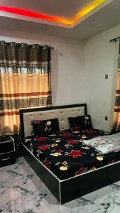 a bedroom with a bed with a black bedspread with flowers at Bright Moon Hotel limited in Enugu