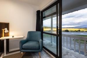a room with a chair and a balcony with a view at Alpine Chalets in National Park