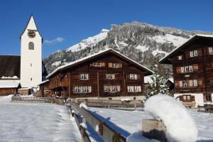 un edificio cubierto de nieve con una iglesia y una montaña en Apartment Sandgasse en Elm