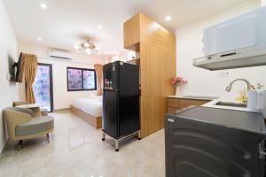 a kitchen with a black refrigerator and a bedroom at The Pivot Suite Ben Thanh - District 1 in Ho Chi Minh City