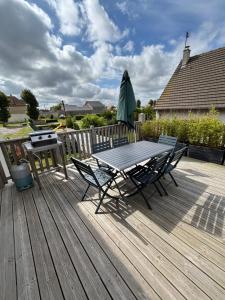a wooden deck with a table and chairs and an umbrella at La Maison des phares in Lion-sur-Mer