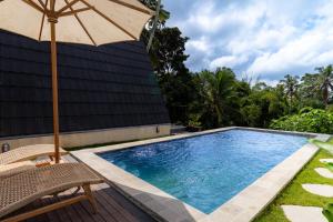 an umbrella and a chair next to a swimming pool at Green Tara Valley Ubud by Betterplace in Ubud +21 photos