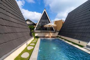 a house with a swimming pool between two buildings at Green Tara Valley Ubud by Betterplace in Ubud