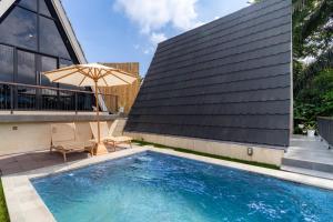 a swimming pool with an umbrella next to a building at Green Tara Valley Ubud by Betterplace in Ubud