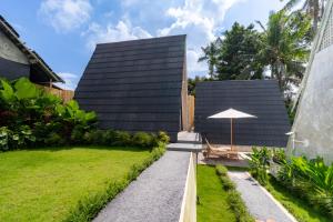 an external view of a house with a lawn and an umbrella at Green Tara Valley Ubud by Betterplace in Ubud