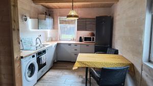 a kitchen with a table and a sink and a washing machine at Leśne Doliny 38 in Zwiartów
