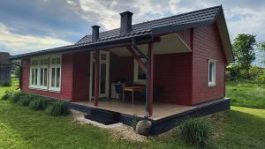 a red house with a wooden deck in the grass at Leśne Doliny 38 in Zwiartów