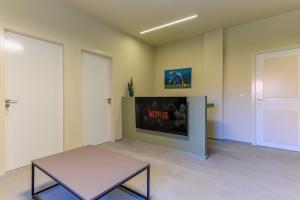 a room with a table and a tv on a wall at Capri 2-BR Apartment In Bahsa Batroun in Batroûn