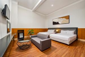 a hotel room with two beds and a couch at Eluna Lilly Da Lat Hotel in Da Lat