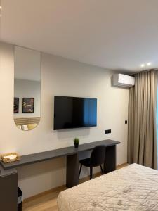 a bedroom with a desk with a television on a wall at Luxor Suites Olimpou in Thessaloniki