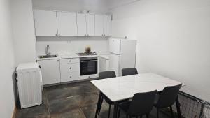 a kitchen with white cabinets and a table and chairs at Apartment 42 in Ljubuški