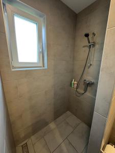 a bathroom with a shower with a window at Primera Apartments in Palić