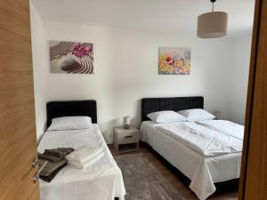 two beds in a room with white walls at Primera Apartments in Palić