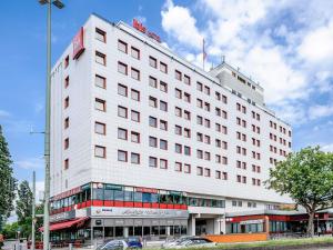 a large white building with cars parked in front of it at ibis Berlin Messe in Berlin