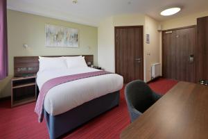 a hotel room with a bed and a desk and chair at Fire Service College in Moreton in Marsh