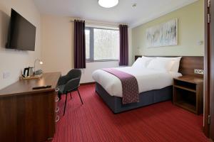 a hotel room with a bed and a desk and a television at Fire Service College in Moreton in Marsh