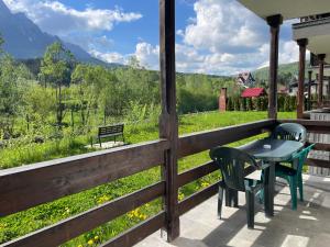 a porch with a table and chairs and a view of a field at Cozy Riverfront Apartments with garden and mountain view in Buşteni