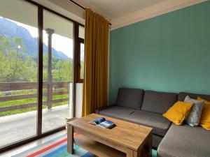 a living room with a couch and a table at Cozy Riverfront Apartments with garden and mountain view in Buşteni