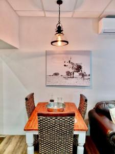 a dining room with a wooden table with a cow on the wall at The Stetson - Paarl - Self Catering Apartment in Paarl